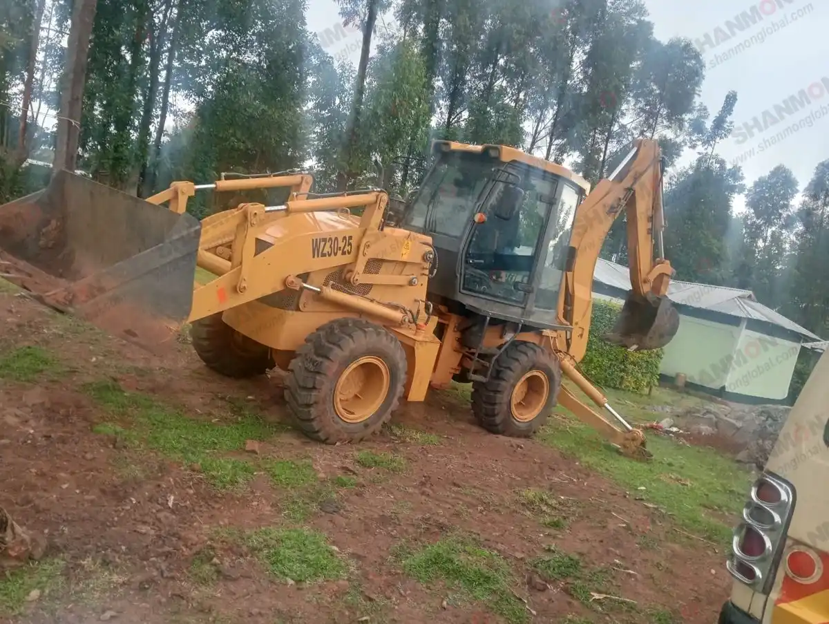 Shanmon WZ30-25 backhoe loader parked beside homes at Kenyan construction site